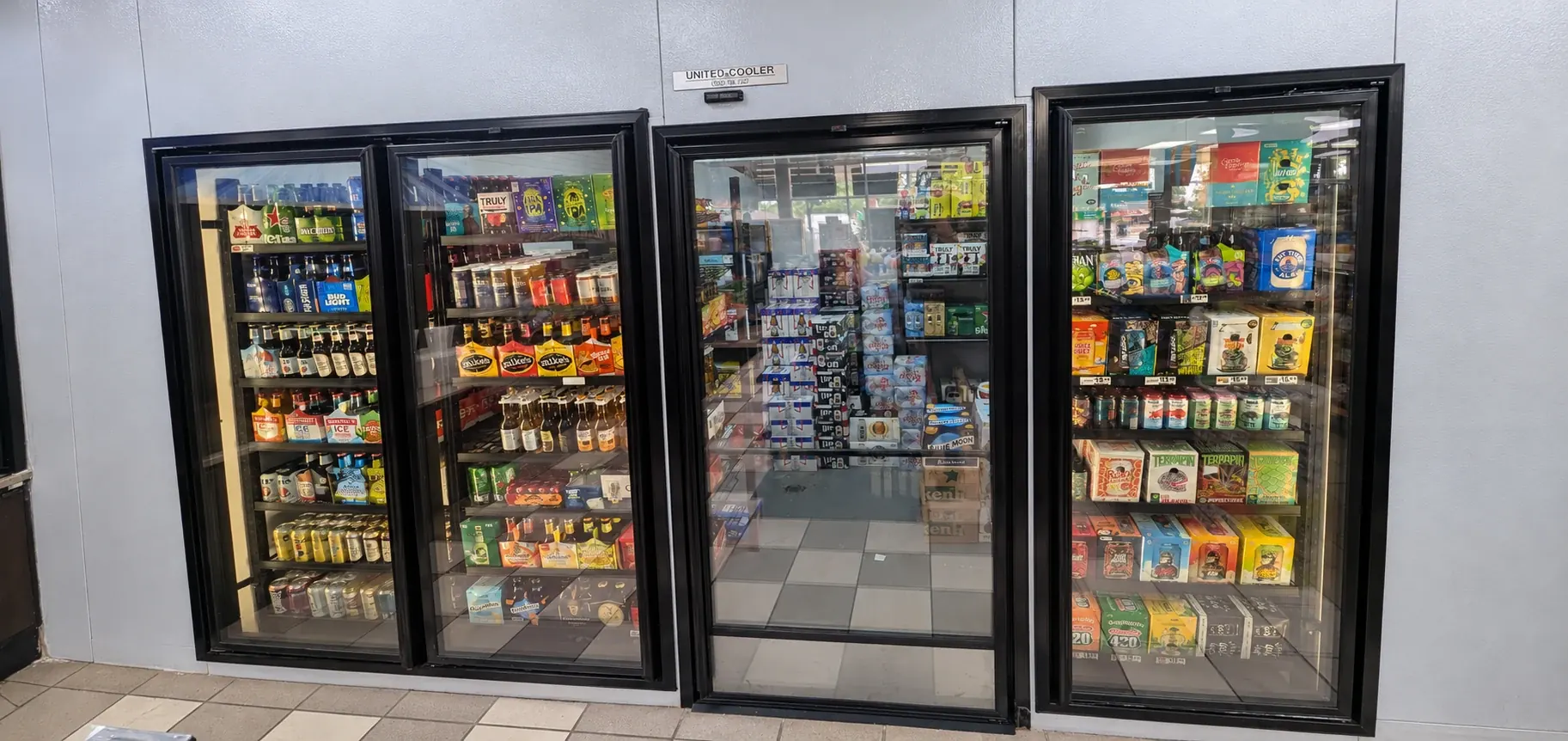 Stocked glass-door beer cooler with a central walk-in entrance