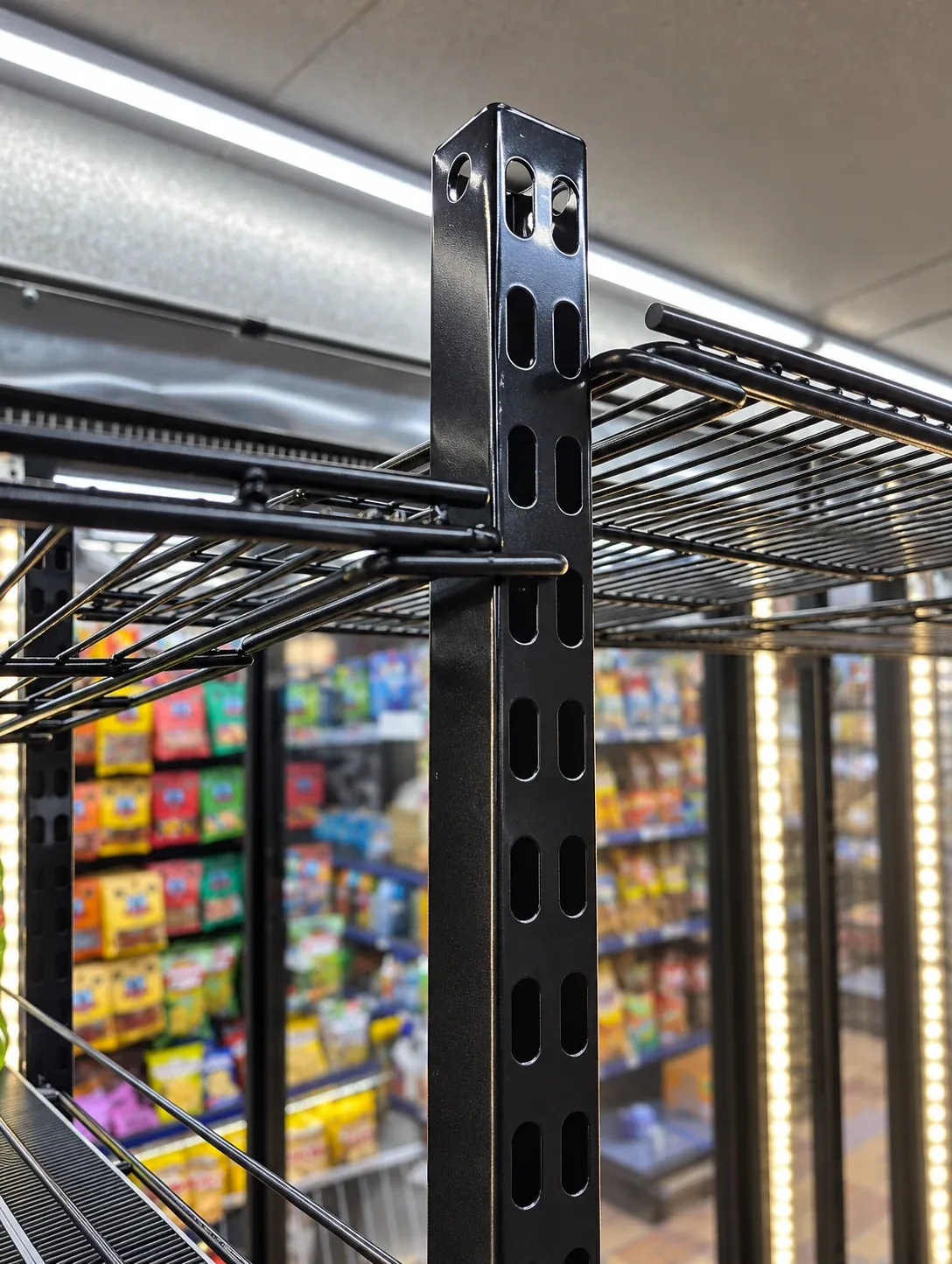 Black slotted shelving post supporting wire shelves